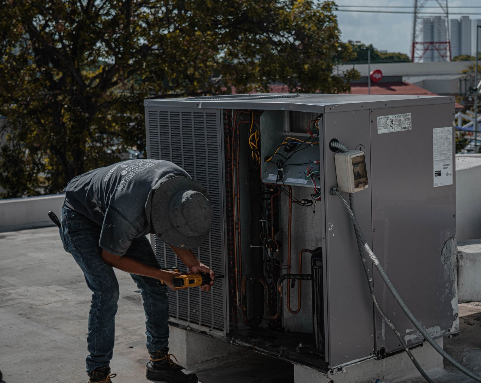 A Climate Control AC technician servicing the open access panel of a rooftop package HVAC unit under the southern Utah sky