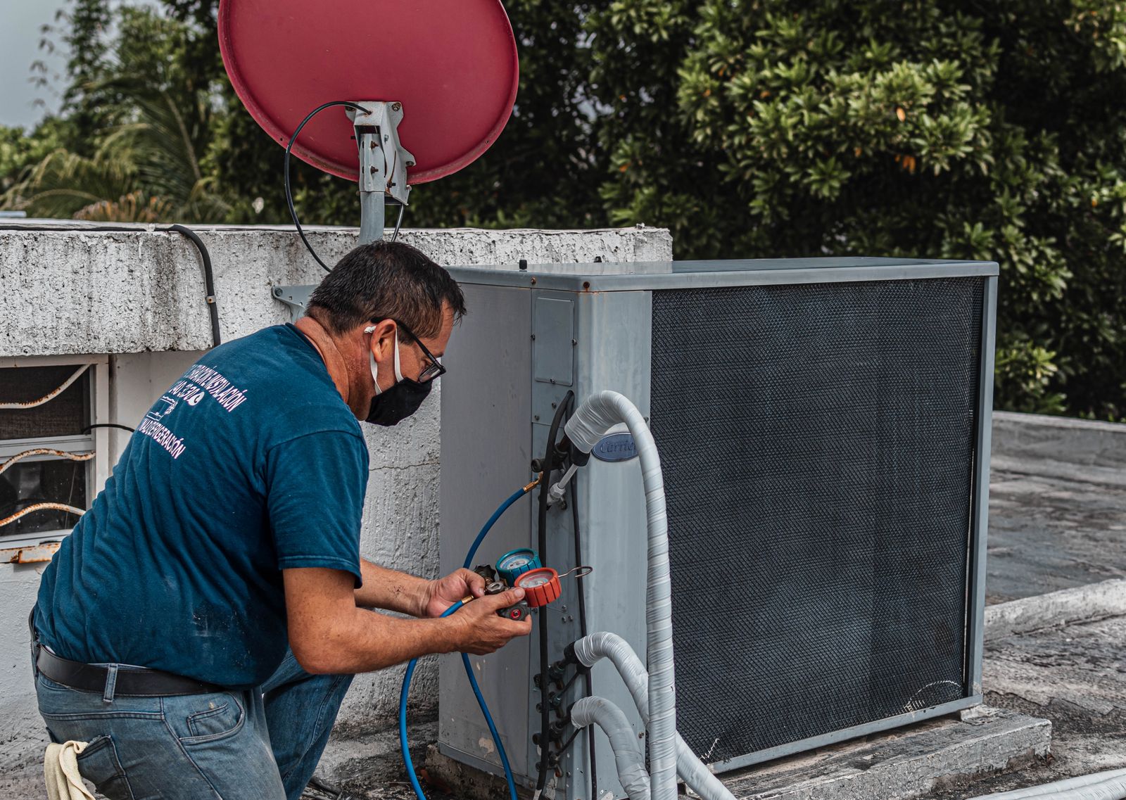 A Climate Control AC technician using refrigerant manifold gauges to service an outdoor air-conditioning unit